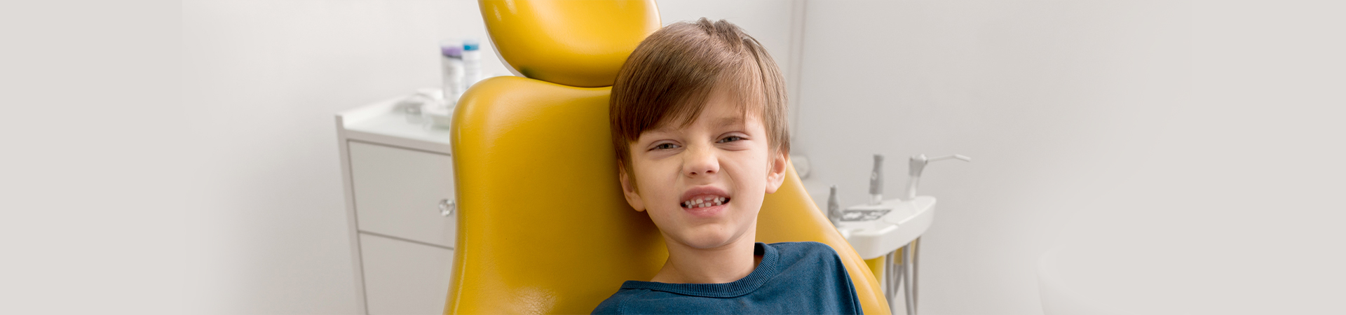 A young patient smiles in a dental chair, surrounded by a dentist and assistant, highlighting a friendly dental environment at New Smile Dentistry.